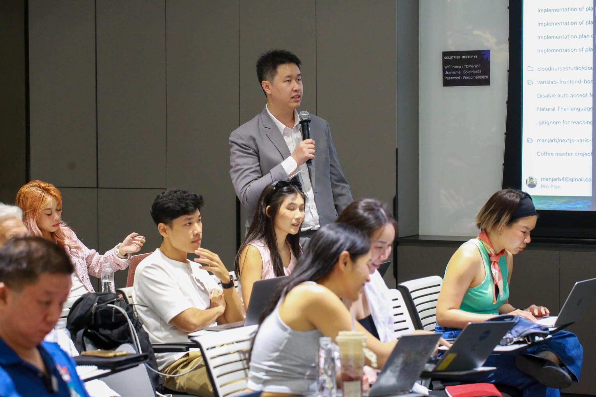 ผู้เข้าร่วมงานยืนขึ้นถามคำถามในงาน SoloTribe Meetup #1 ขณะที่ทั้งห้องกำลังลงมือทำกับโน้ตบุ๊ก